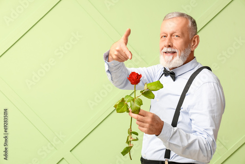 Mature man pointing at rose...