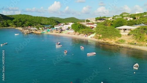 Aerial flyover of red white fishing boats anchored in sand off coast of Boca Sami, Curacao photo