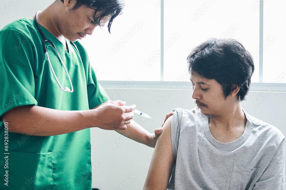 Male doctor with syringe doing injection of vaccine to patient in the hospital Male doctor with syringe doing injection of vaccine to patient in the hospital