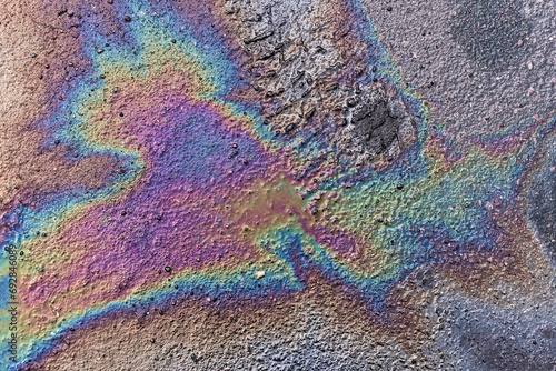 Gasoline spot on wet asphalt. Multi colored oil spill on asphalt road  abstract background  texture