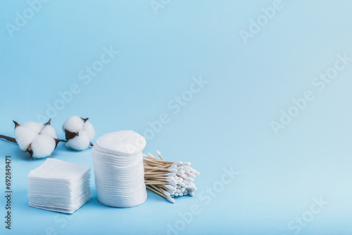 Bamboo eco cotton swabs and cotton pads of different shapes for personal hygiene and a cotton flower on a blue background. Copy space. photo