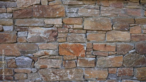 The side of a stone built cabin lodge showing the range of different size and shaped stones used to build the space with sideways movement in slow motion photo