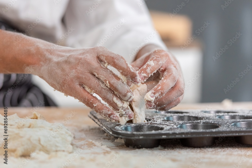 professional Chef sifting flour powder and sprinkling ingredients on massaging dough for bakery cooking. Chef show dirty finger hand sifting flour wheat and kneading dough mixing powder. - obrazy, fototapety, plakaty 