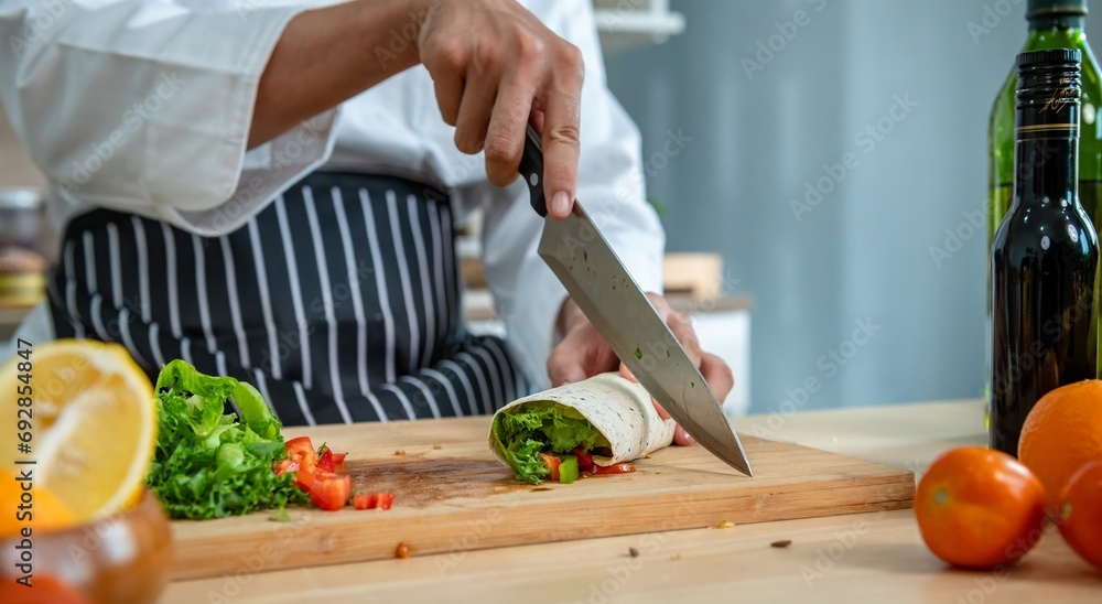chef make tortilla wrap vegetable salad slice by knife on cutting board and mix sour salad dressing in small bowl glass with wine and olive oil. tortillas wrap vegetable and juicy liquid sour dressing - obrazy, fototapety, plakaty 