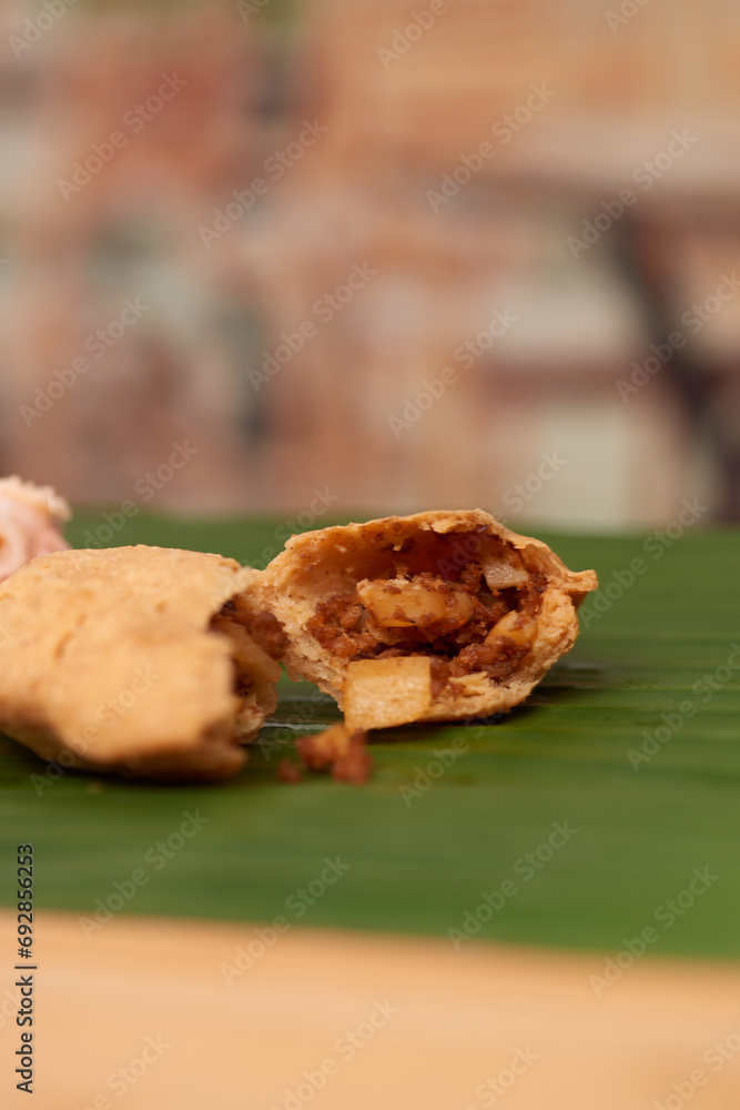 A tempting photo of a savory Salvadoran pastelito, showcasing its authentic taste and culinary artistry, set in a restaurant-style ambiance on a wooden surface accentuated by a leaf A tempting photo of a savory Salvadoran pastelito, showcasing its authentic taste and culinary artistry, set in a restaurant-style ambiance on a wooden surface accentuated by a leaf