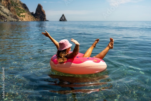 Summer vacation woman in hat floats on an inflatable donut mattress. Happy woman relaxing and enjoying family summer travel holidays travel on the sea.