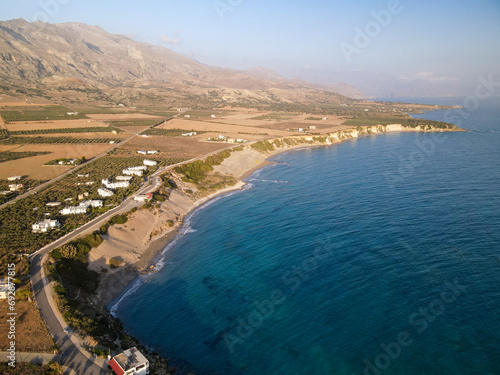 Aerial view of remote southern village in Crete Frangokastello with beautiful natural landscape, olive tree groves and villas, Orthi Ammos cliffs and beach