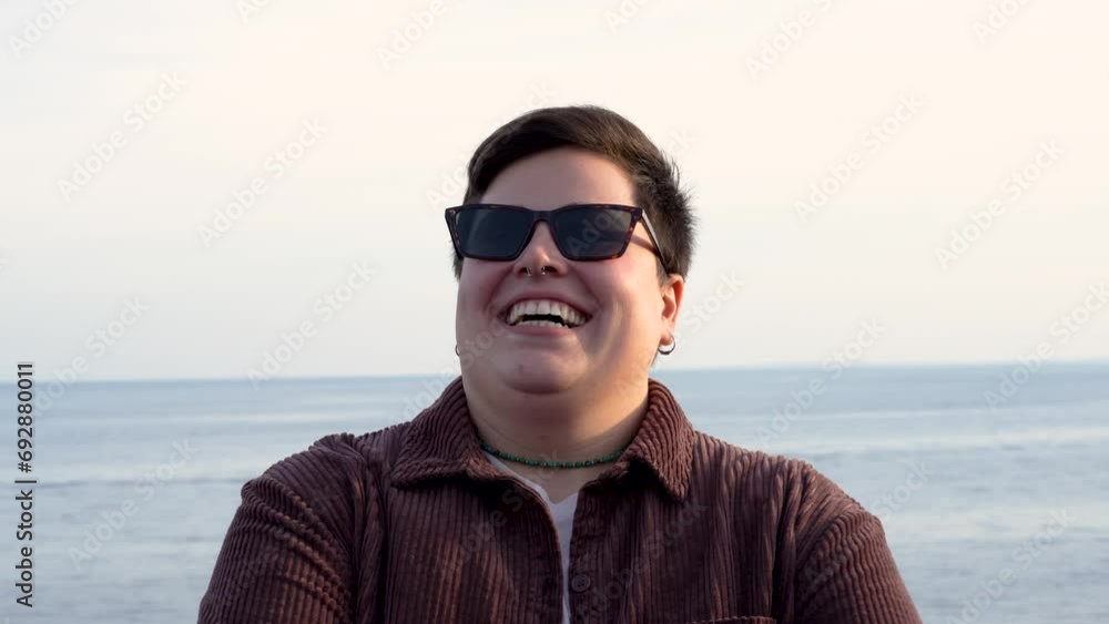 Handsome curvy non-binary woman with sunglasses smiling outdoors seaside - people lifestyle concept Handsome curvy non-binary woman with sunglasses smiling outdoors seaside - people lifestyle concept