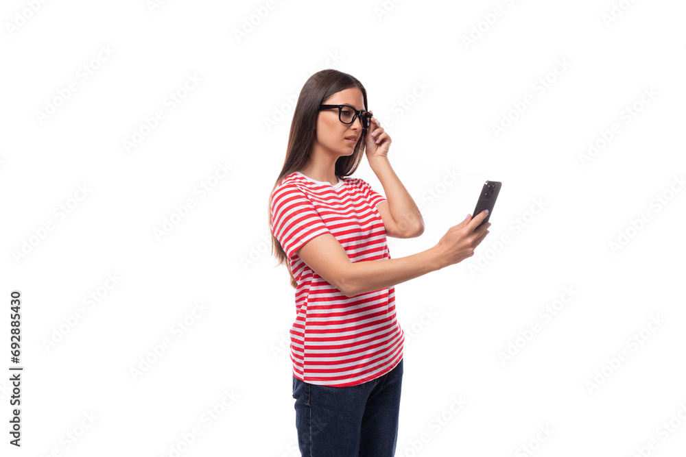 joyful pretty 35 year old european lady in eyeglasses and red striped t-shirt chatting in smartphone