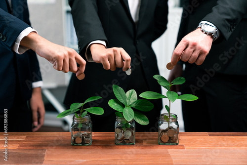 Business people put money saving into jar filled with coins and growing plant for sustainable financial planning for retirement or eco subsidy investment for environment protection. Quaint photo