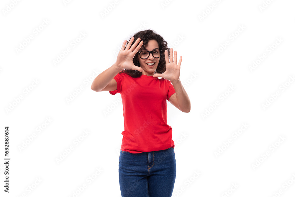 portrait of a young caucasian leader woman with black curly hair dressed in a red basic t-shirt actively gesturing with her hands portrait of a young caucasian leader woman with black curly hair dressed in a red basic t-shirt actively gesturing with her hands