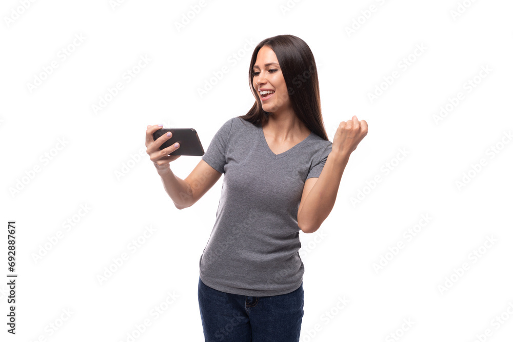 young slender brunette promoter woman dressed in a gray t-shirt uses a smartphone on a white background with copy space young slender brunette promoter woman dressed in a gray t-shirt uses a smartphone on a white background with copy space