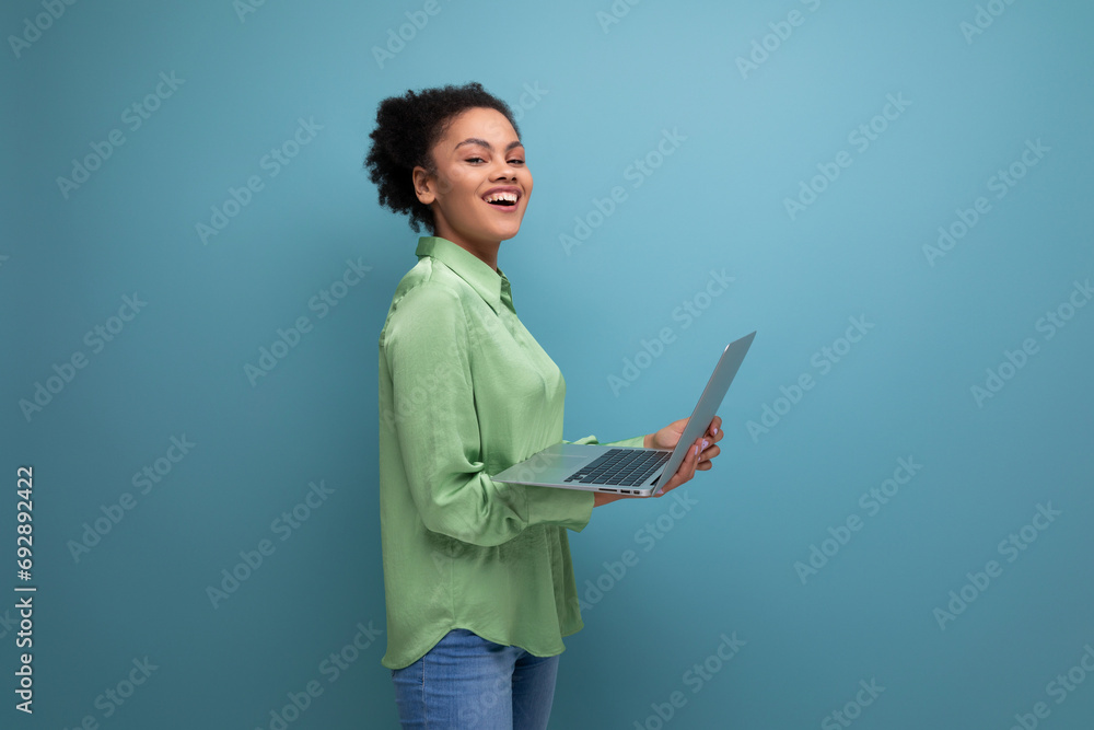 young pretty female model with curly black hair dressed in a green blouse and jeans works remotely using a laptop young pretty female model with curly black hair dressed in a green blouse and jeans works remotely using a laptop