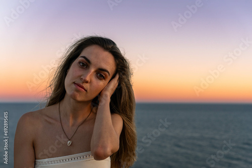 Young tender woman with long hair against sea at sunset