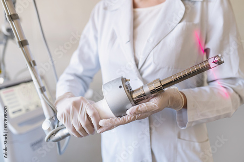 female doctor holds in hands carbon dioxide laser with phallic attachment for vaginal rejuvenation. Hardware cosmetology and medicine. Skin tightening, scar removal, stretch marks and lifting closeup photo