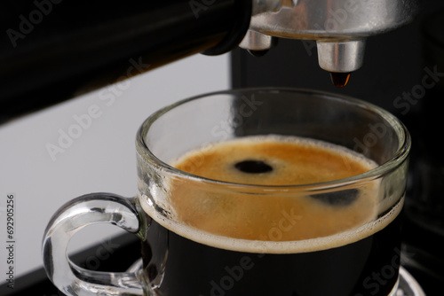 Close up of cup with espresso coffee in coffee maker.