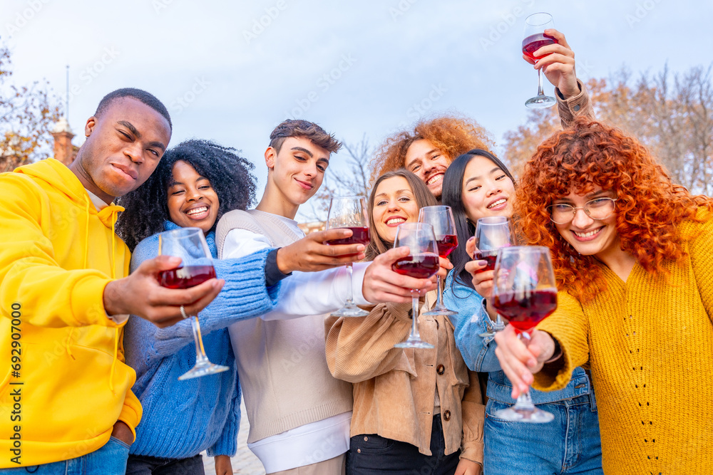 Multi-ethnic friends toasting with red wine in the street Multi-ethnic friends toasting with red wine in the street