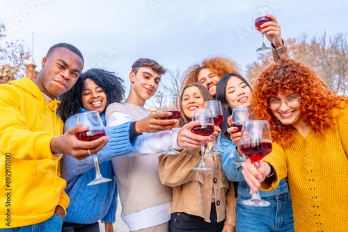 Multi-ethnic friends toasting with red wine in the street