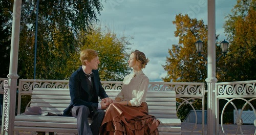 history of 19th century, Caucasian man and woman sitting on bench in park and laughing, 4K, Prores photo