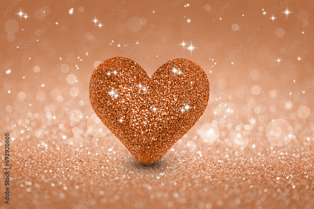 Sparkling beige festive background with pink heart. Holiday greeting card. Demonstrating color of 2024 year - peach.