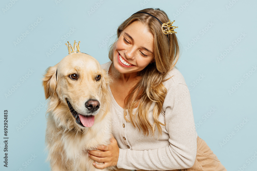 Young fun owner woman wear casual clothes hug cuddle best friend retriever dog with crown diadem celebrating birthday isolated on plain pastel light blue background studio Take care about pet concept