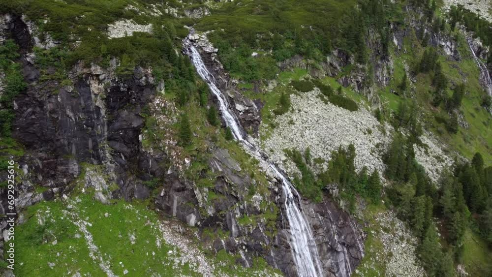 Huge waterfall surrounded by a lot of gravel and a few trees leading down a cliff in the Alps in Kaernten, Austria. Huge waterfall surrounded by a lot of gravel and a few trees leading down a cliff in the Alps in Kaernten, Austria.