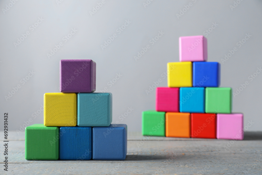 Pyramids of blank colorful wooden cubes against light grey background, selective focus Pyramids of blank colorful wooden cubes against light grey background, selective focus