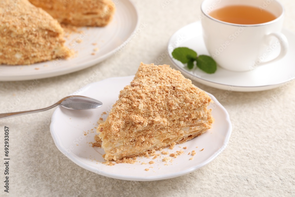 Piece of delicious Napoleon cake served on beige table, closeup Piece of delicious Napoleon cake served on beige table, closeup