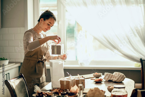 A female bakery owner packs boxes for a customer's order into a birthday, Christmas package. A small business entrepreneur and the concept of food delivery. photo