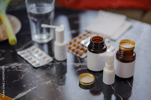 A handful of pills scattered on the table. A vial of medicines. Marble surface. Nobody in space with medical treatment, tablets of capsules, bottles of pills for ill person