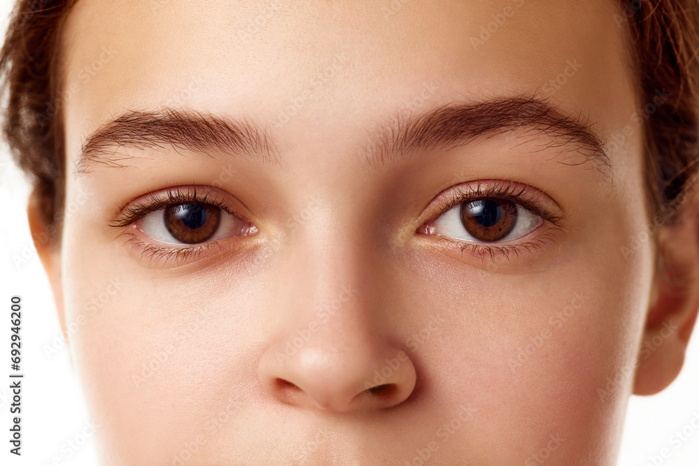 Fototapeta premium Close-up image of beautiful young girl with smooth, healthy, well-kept skin, brown eyes standing against white background. Concept of natural female beauty, skin care, cosmetology and cosmetics