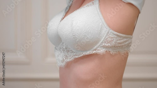 Beautiful female slowly removing blouse revealing sexy white lingerie bra photo
