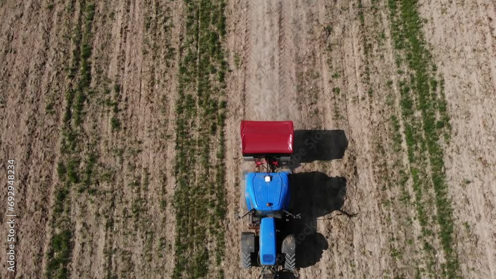 Blue tractor spreading dry fertilizer on the field in Spain Blue tractor spreading dry fertilizer on the field in Spain
