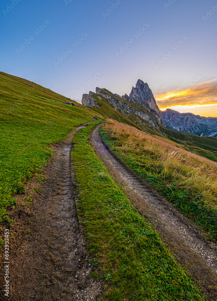 Sunrise at Seceda, Dolomites, Italy, Golden hues embrace the rugged landscape and meadows, unveiling a breathtaking morning panorama, serene and radiant in its natural beauty.