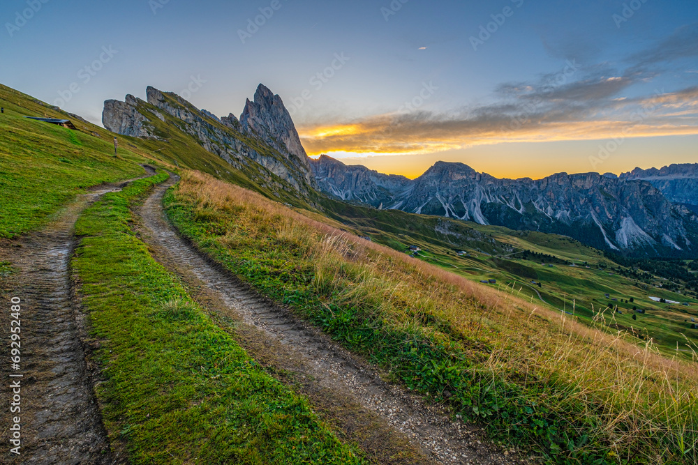 Golden sunrise at Seceda, Dolomites, Italy, A stunning spectacle bathes the rugged landscape and meadows in warm hues, creating a serene and radiant morning panorama.