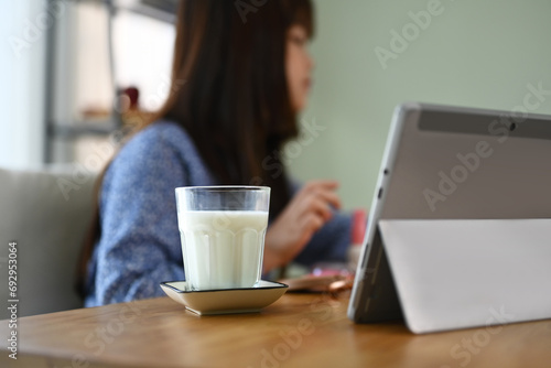 A glass and bottle of milk on wooden table with child girl doing homework on background