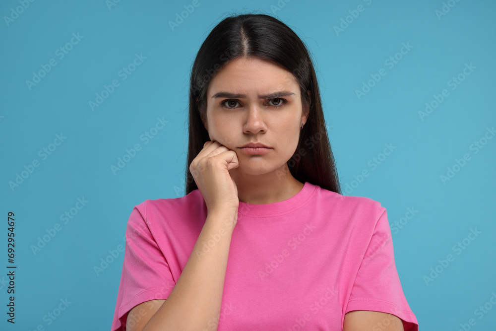 Portrait of resentful woman on light blue background Portrait of resentful woman on light blue background