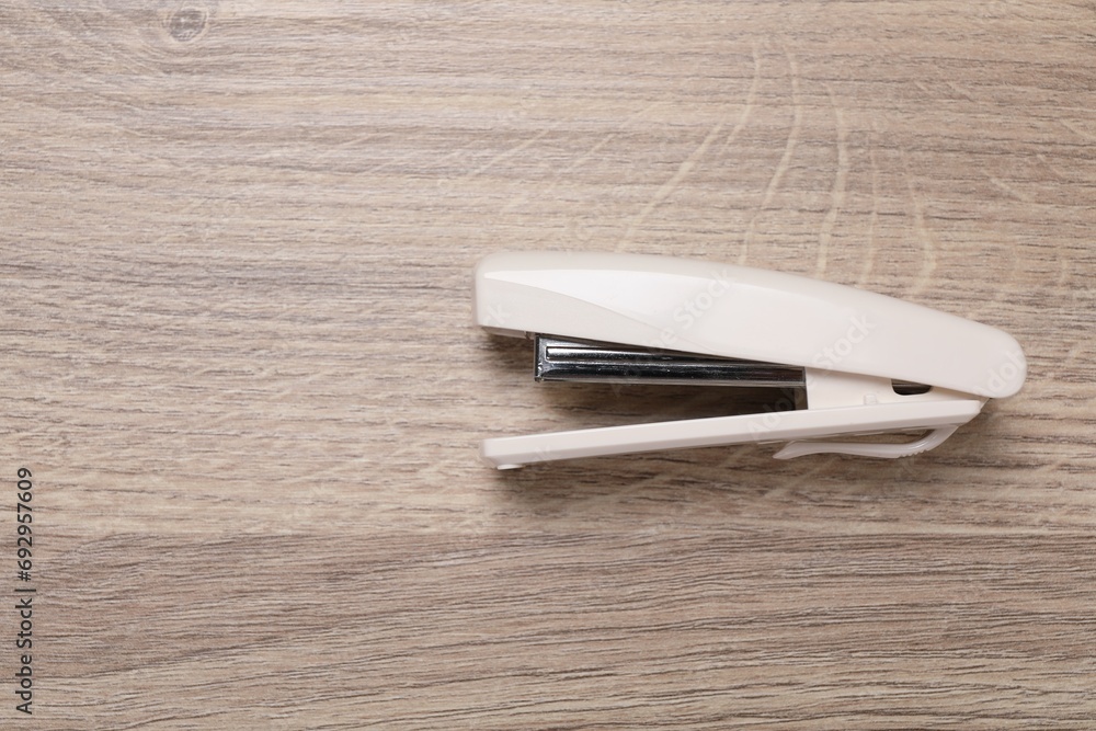 One beige stapler on wooden table, top view. Space for text One beige stapler on wooden table, top view. Space for text