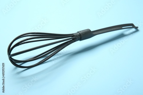 One whisk on light blue background, closeup
