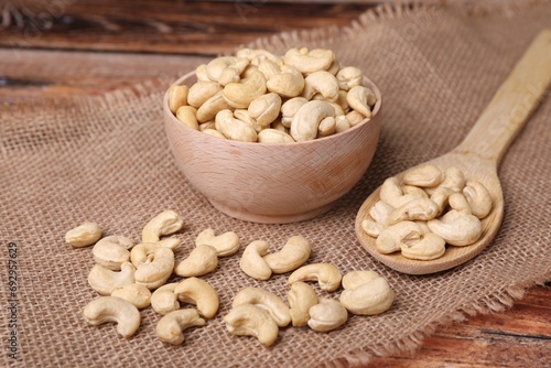 Tasty cashew nuts in bowl and spoon on table