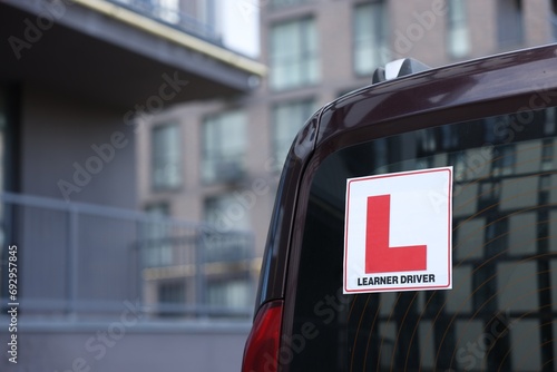 L-plate on car outdoors, closeup with space for text. Driving school photo