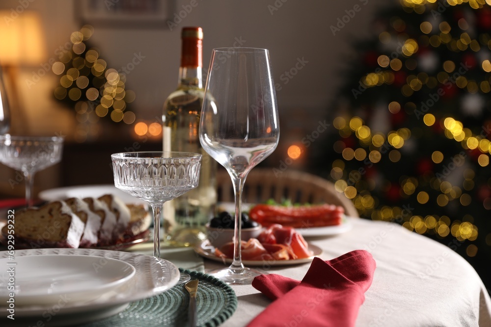 Christmas table setting with bottle of wine, appetizers and dishware indoors