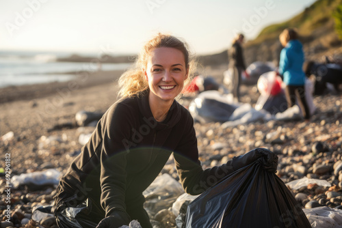 A smiling female volunteer picking up plastic litter on a beach and making a positive impact on the environment