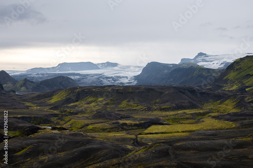Volcano Eyjafjallajökull with snow and green moss on hills on Icelandic highlands at Landmannalaugar, Iceland. Famous Laugavegur hiking trail with dramatic sky. Trekking, hiking concept
