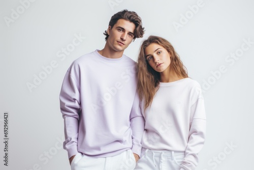 Happy young smiling couple of woman and man wearing lilac sweatshirt on white background.