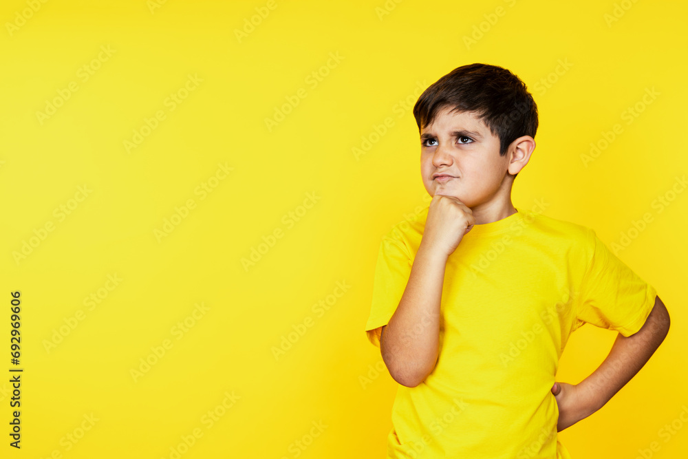 Thoughtful caucasian boy in matching yellow, contemplating seriously with a hand on his chin. Thoughtful caucasian boy in matching yellow, contemplating seriously with a hand on his chin.