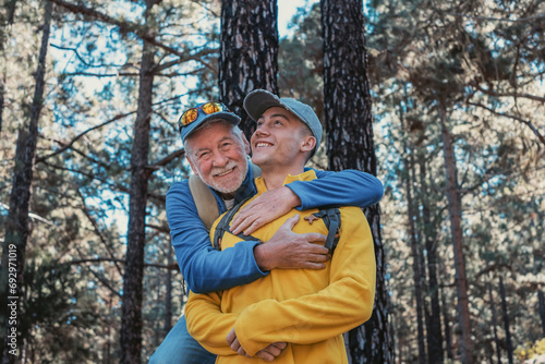 Photos Happy family couple of grandfather and young grandson hugging while hiking in the mountains expressing joy and freedom, healthy lifestyle together in the woods