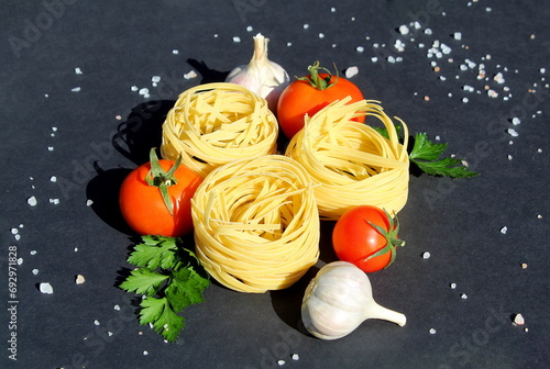 Pasta in the form of a nest with vegetables lies on a black background. 