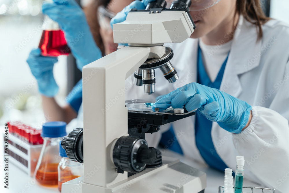 Team of biochemical research scientists working with a microscope for vaccine development. Team of biochemical research scientists working with a microscope for vaccine development.