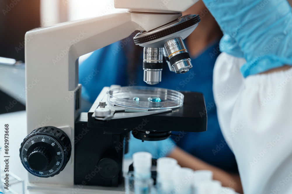 Team of biochemical research scientists working with a microscope for vaccine development. Team of biochemical research scientists working with a microscope for vaccine development.